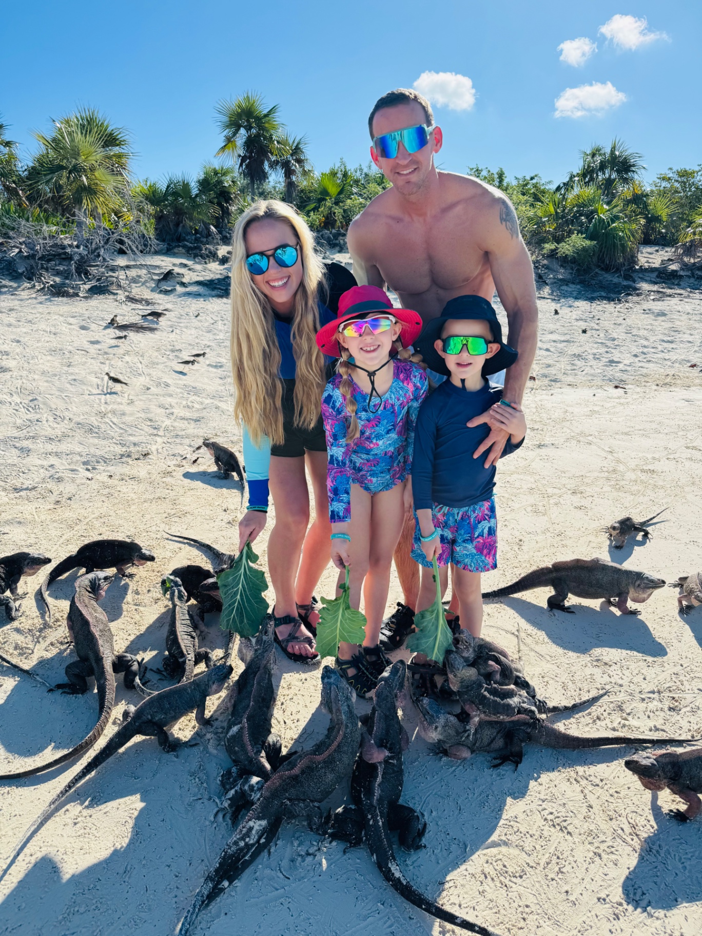 The Venture Seekers family standing on a white sand beach in Exuma surrounded by wild iguanas