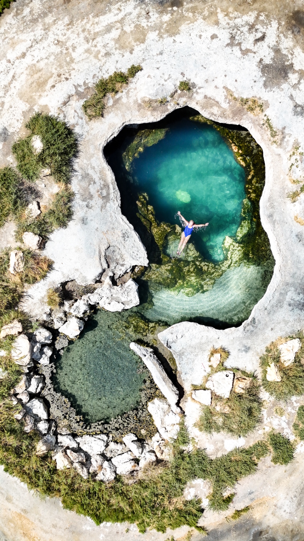 Aerial drone view of Meadow Hot Springs in Utah, three deep blue geothermal pools set in an open desert pasture